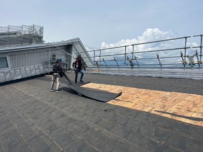 解体作業。新築時のルーフィングをはがすと下地の構造用合板が現れる。合板に腐食がないかも確認